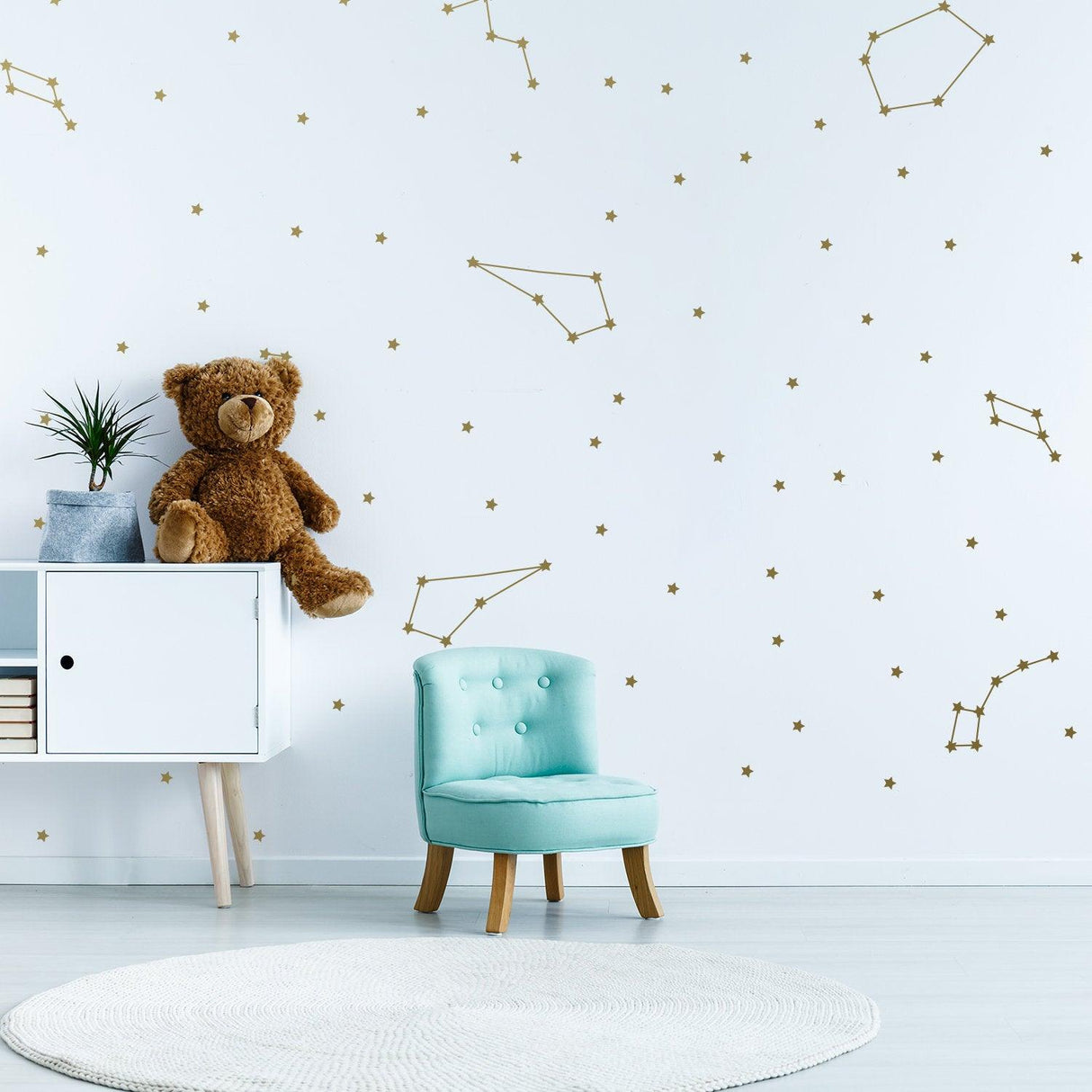 Room decorated with gold constellation wall stickers, featuring a teddy bear and a blue chair.