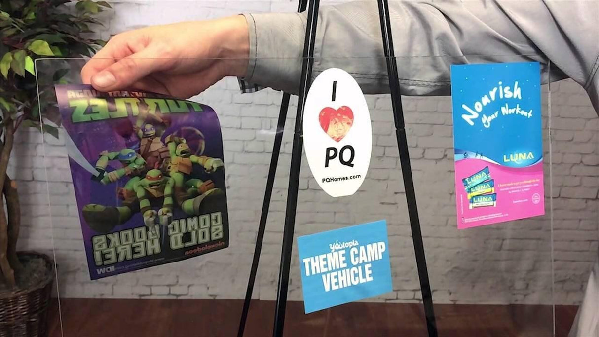 Hand holding various custom static cling vinyl stickers on a display board showcasing designs and branding options.