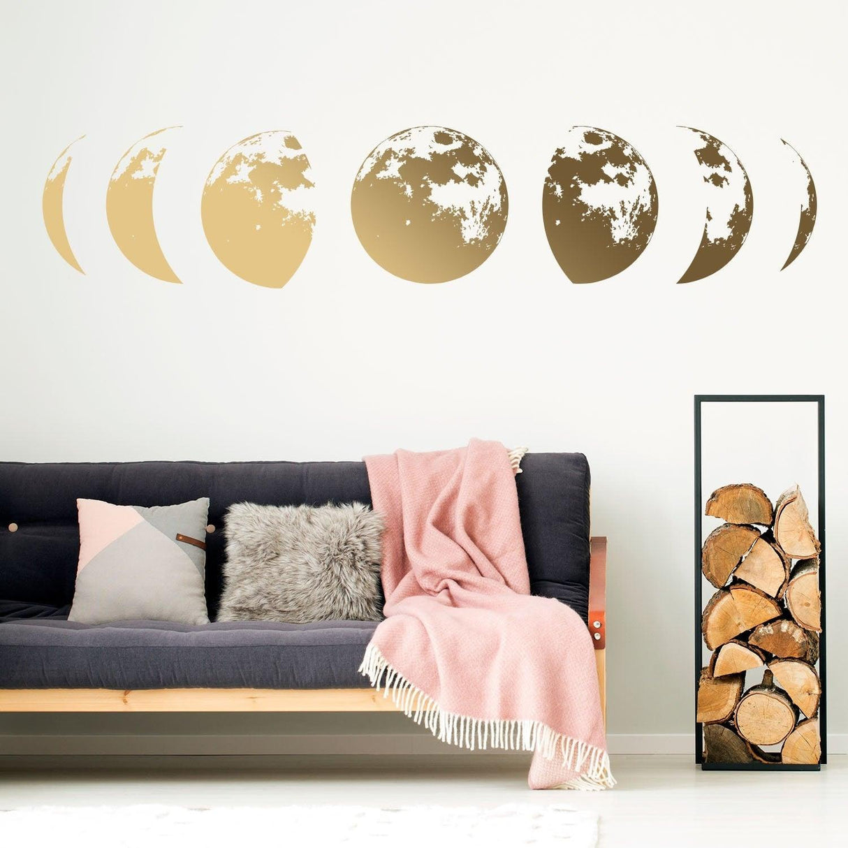 Gold moon phases wall decal above a cozy couch with blankets, enhancing home decor in a stylish living room.