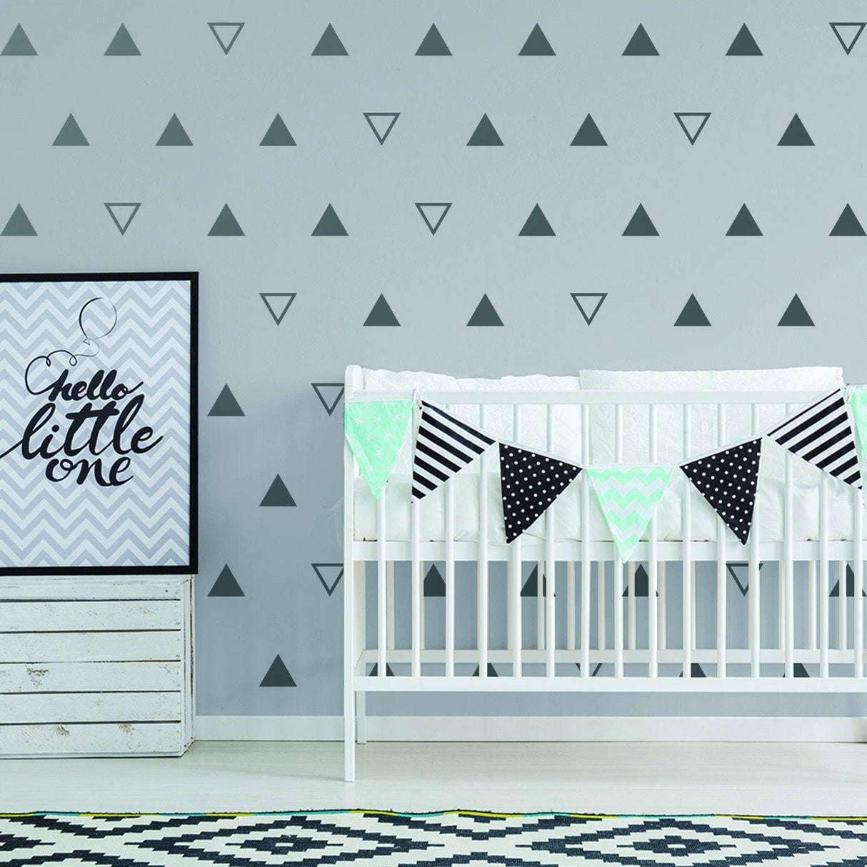 Nursery decor featuring 40x triangle wall vinyl decals in black on a gray wall, with a crib and decorative banners.