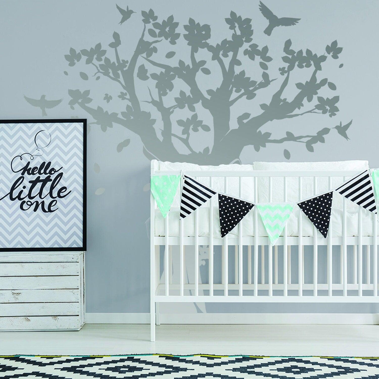 Tree wall decal in nursery with black and white crib, banner, and art print, adding charm to kids room decor.
