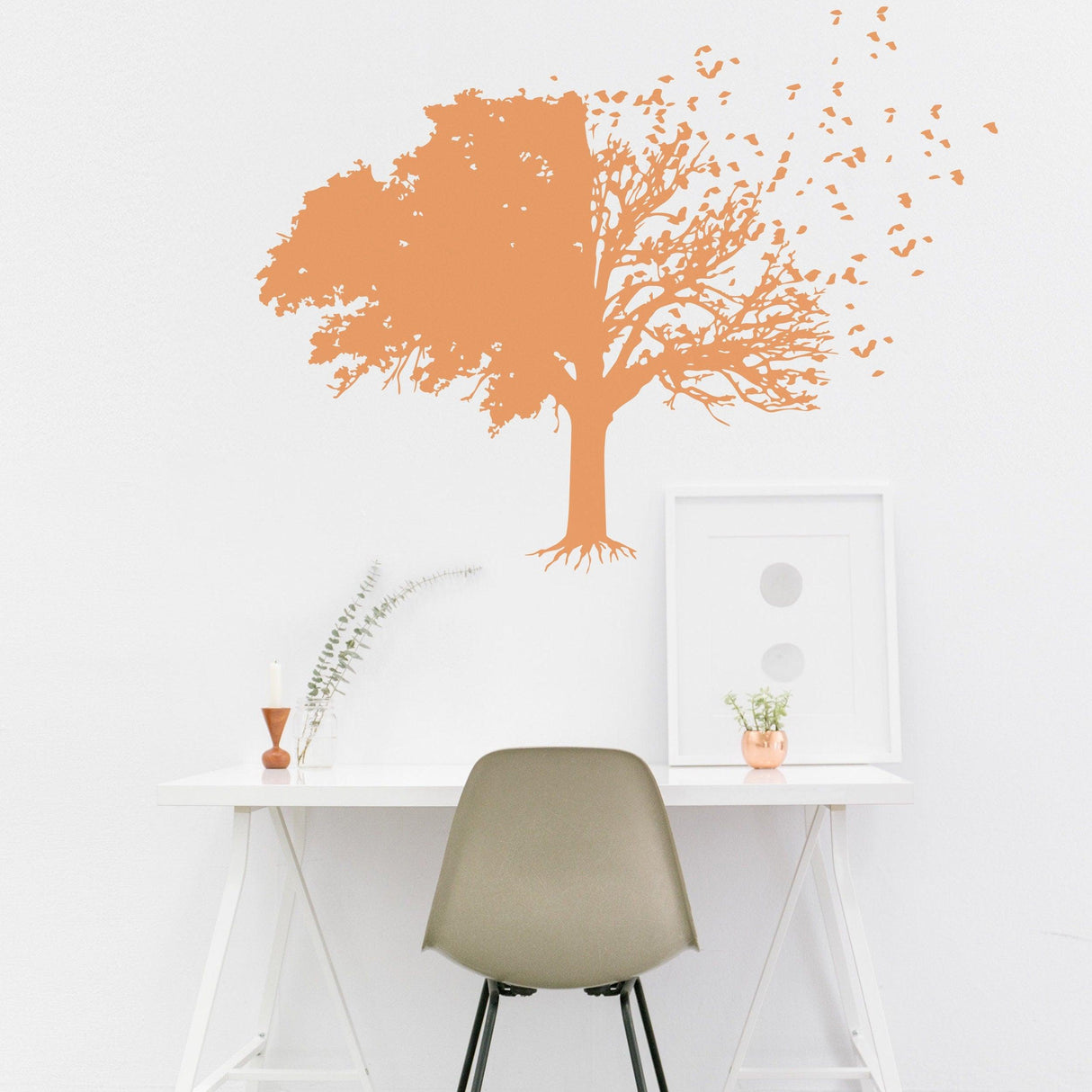 Tree wall decal in orange color on a white wall above a minimalist desk, adding nature-inspired decor to the room.