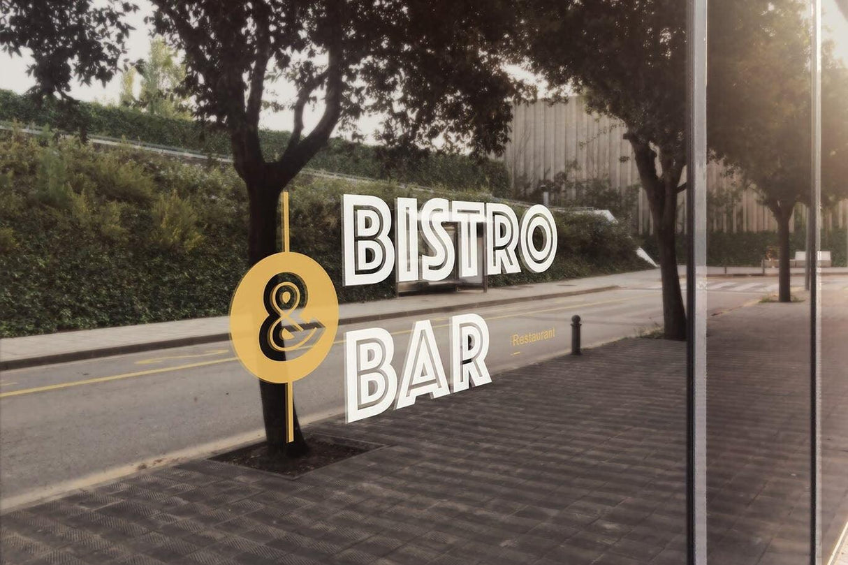 Reflection of a bistro and bar sign displayed on a glass window with trees in the background.