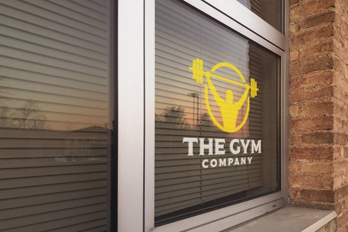 Custom static cling vinyl sticker on gym window featuring logo and weightlifting design.