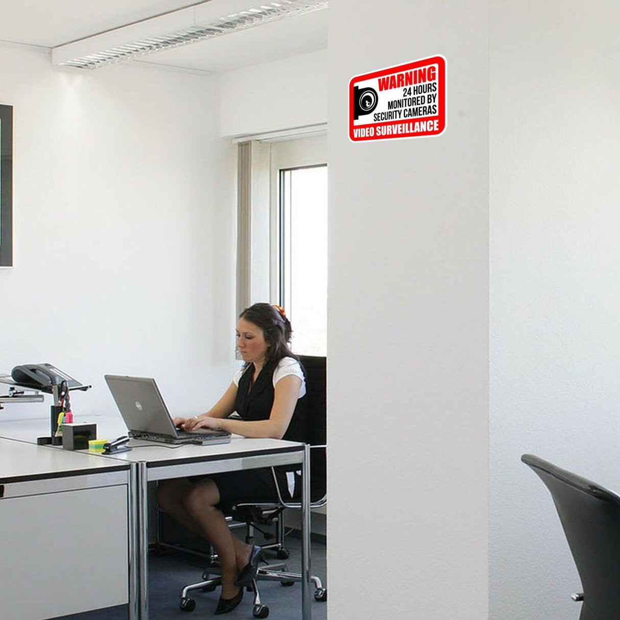 Office with a security camera warning sign on the wall, indicating 24-hour video surveillance for security.