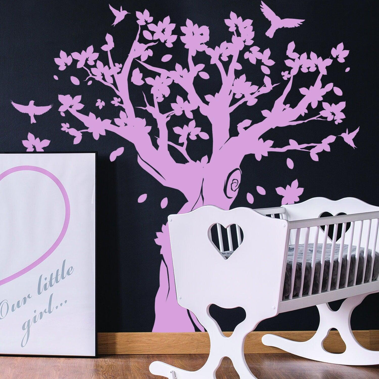 Large pink tree wall decal in nursery with crib and framed artwork, adding charm and whimsy to kids' room decor.