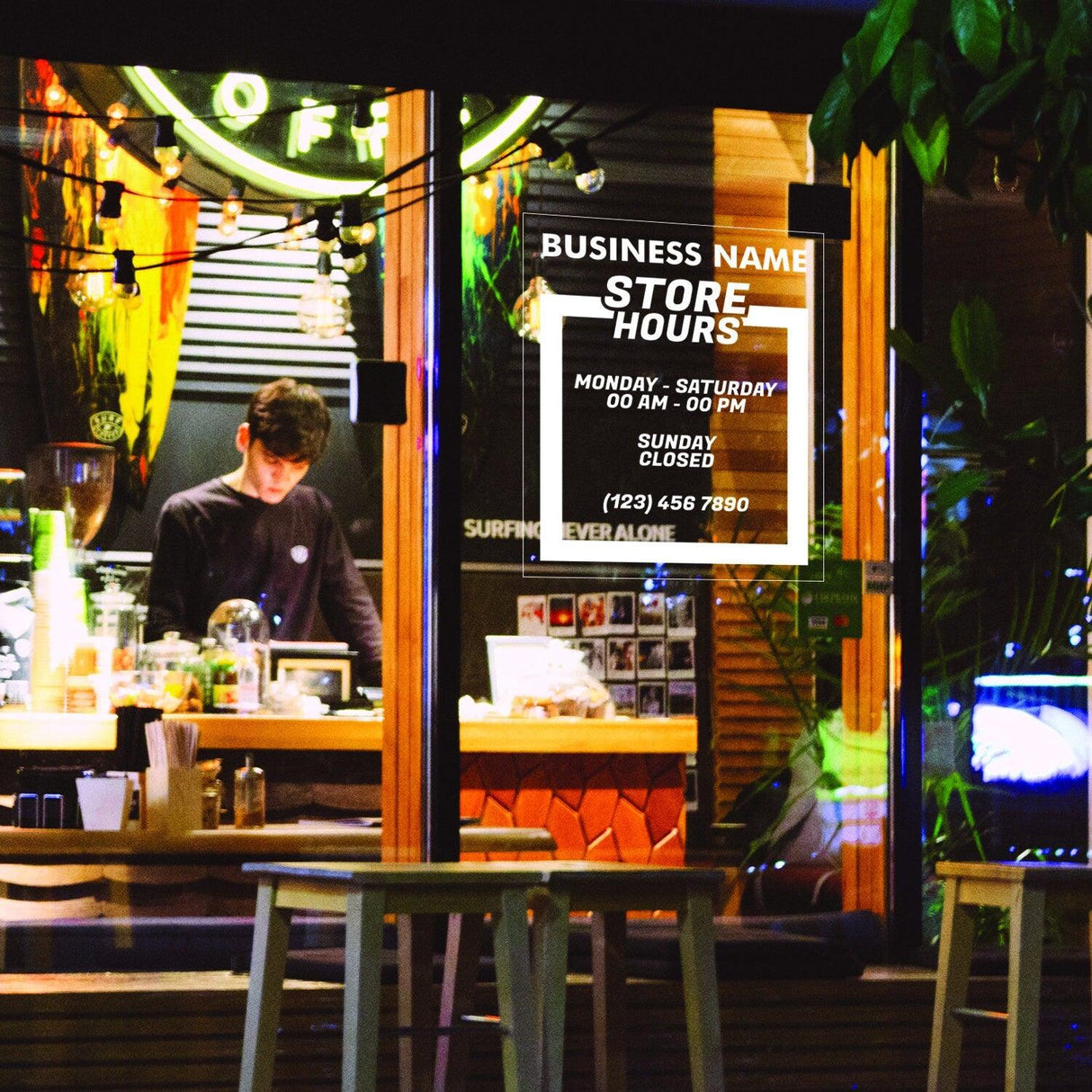 Custom store hours vinyl sign displayed in a shop window with a staff member inside.