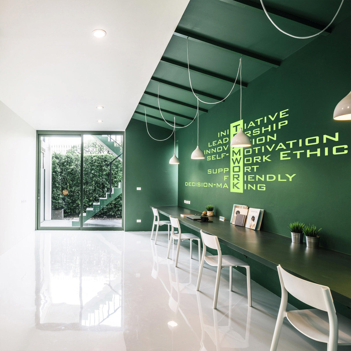 Modern office interior featuring teamwork motivational quotes on a green wall with sleek furniture.