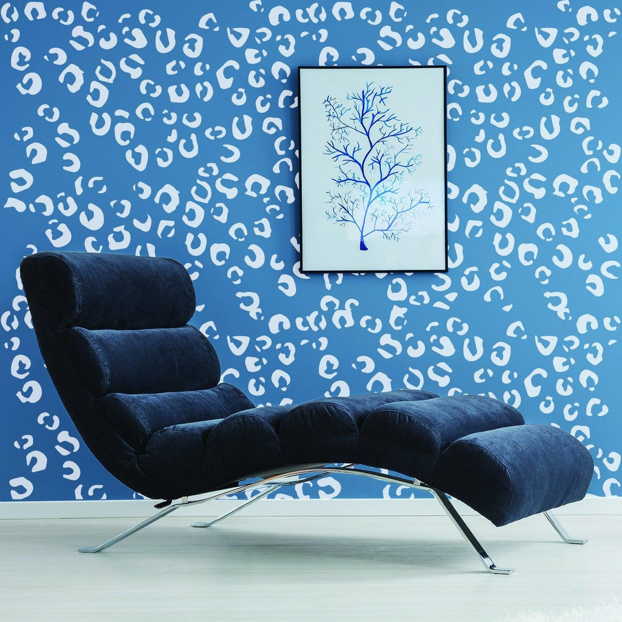 Stylish lounge chair against a blue leopard print wall with a framed tree artwork.