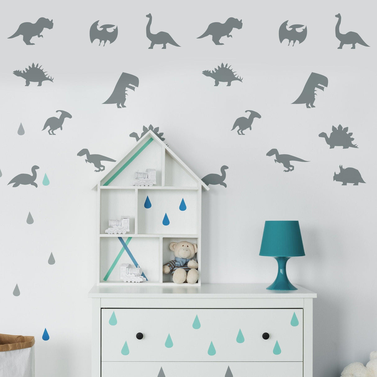 Dinosaur silhouette wall decals in a baby room featuring various dinosaur designs and a decorative shelf.