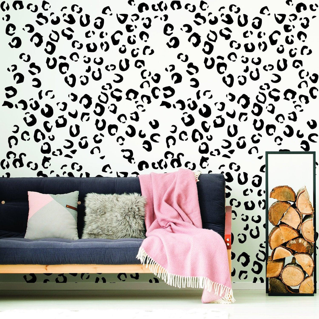 Leopard animal print wallpaper design behind a cozy sofa with blankets and decorative pillows.