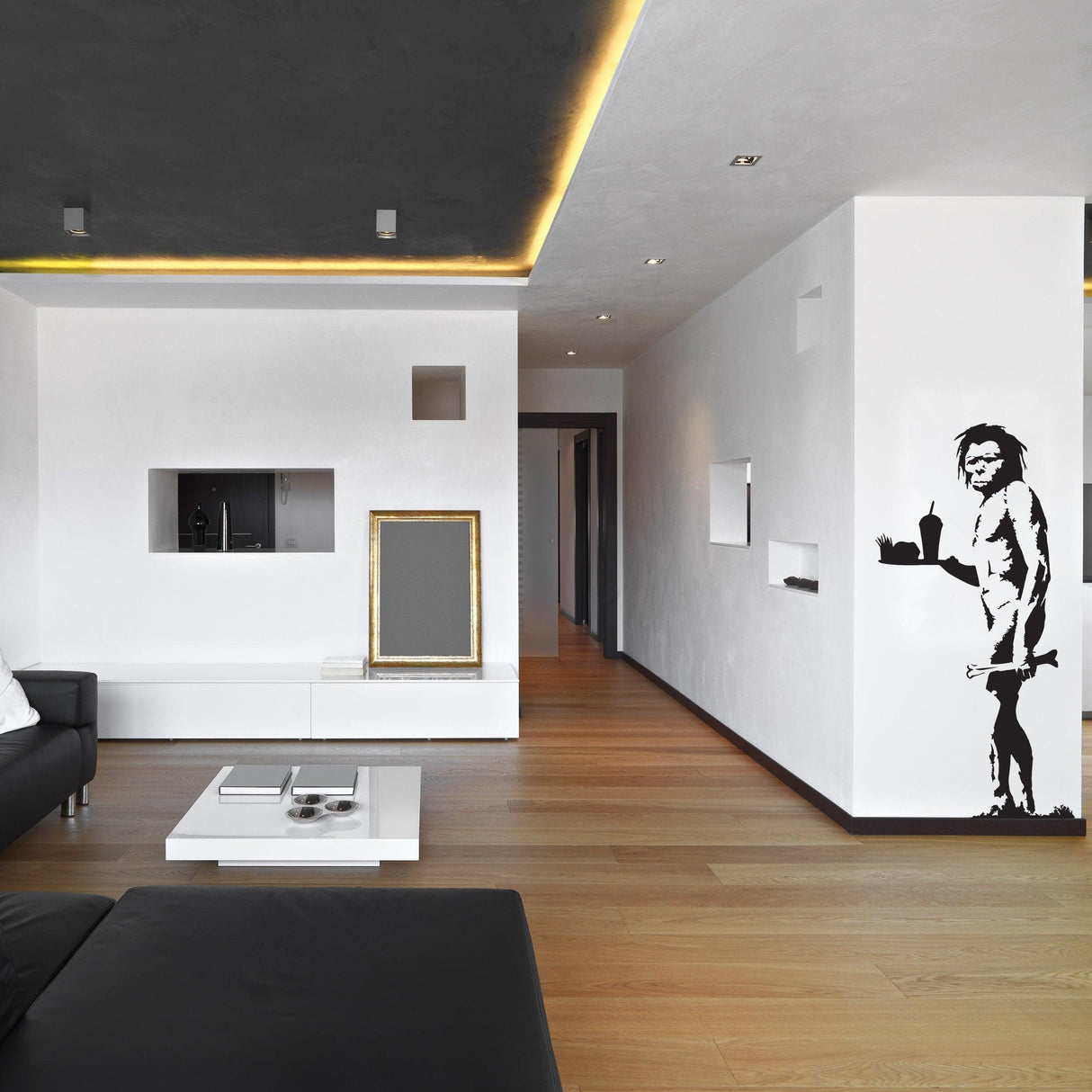 Modern living room featuring Banksy Caveman graffiti vinyl wall decal on a white wall.