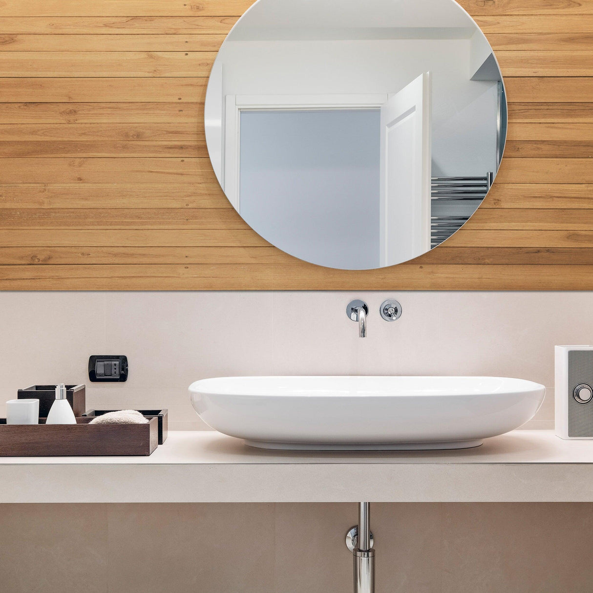 Modern bathroom with round mirror and stylish shiplap wall, featuring a white vessel sink and wooden storage.