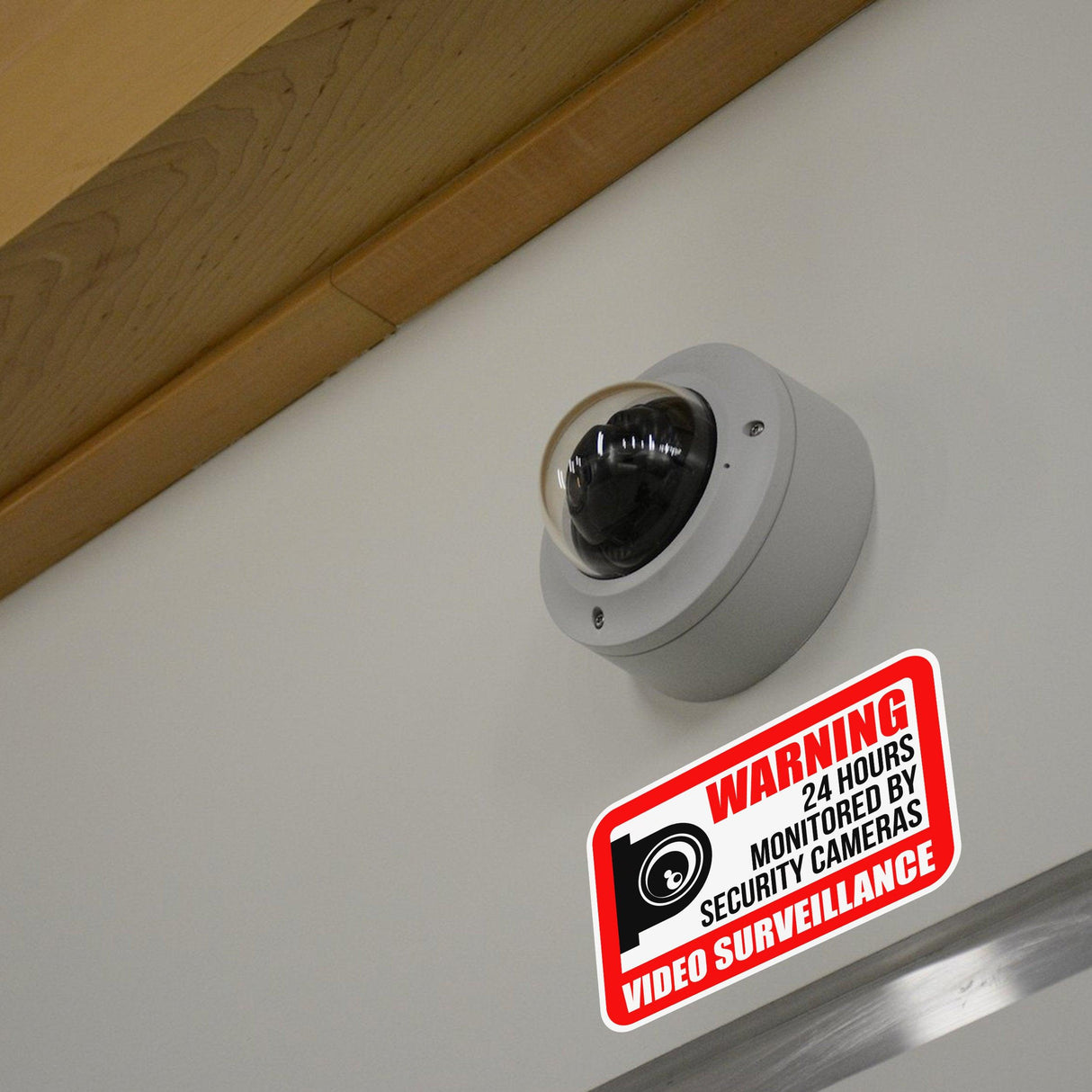 Video surveillance camera with a warning sign indicating 24-hour monitoring for security purposes.