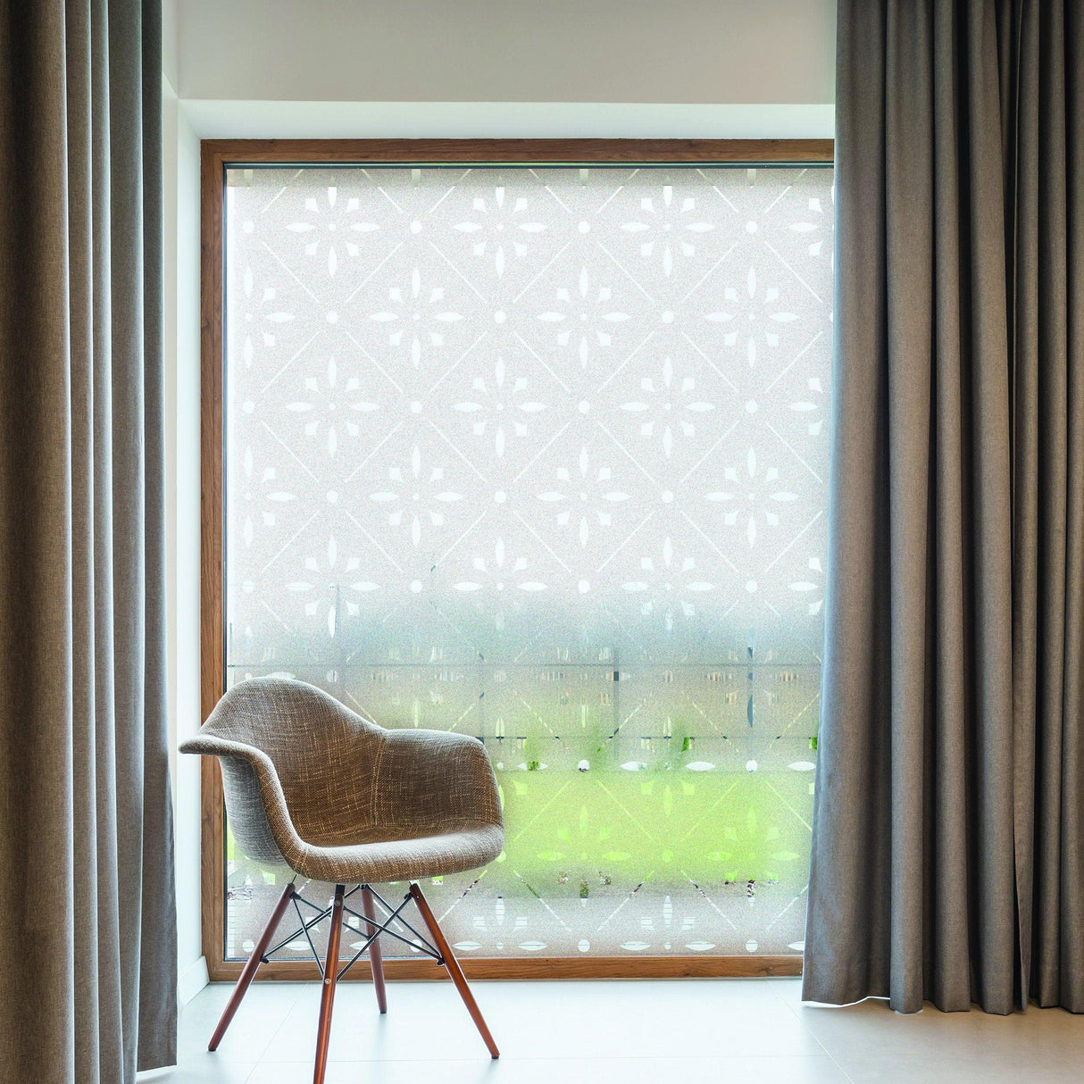 Frosted window decal in a modern room with a chair and gray curtains for added privacy and style.