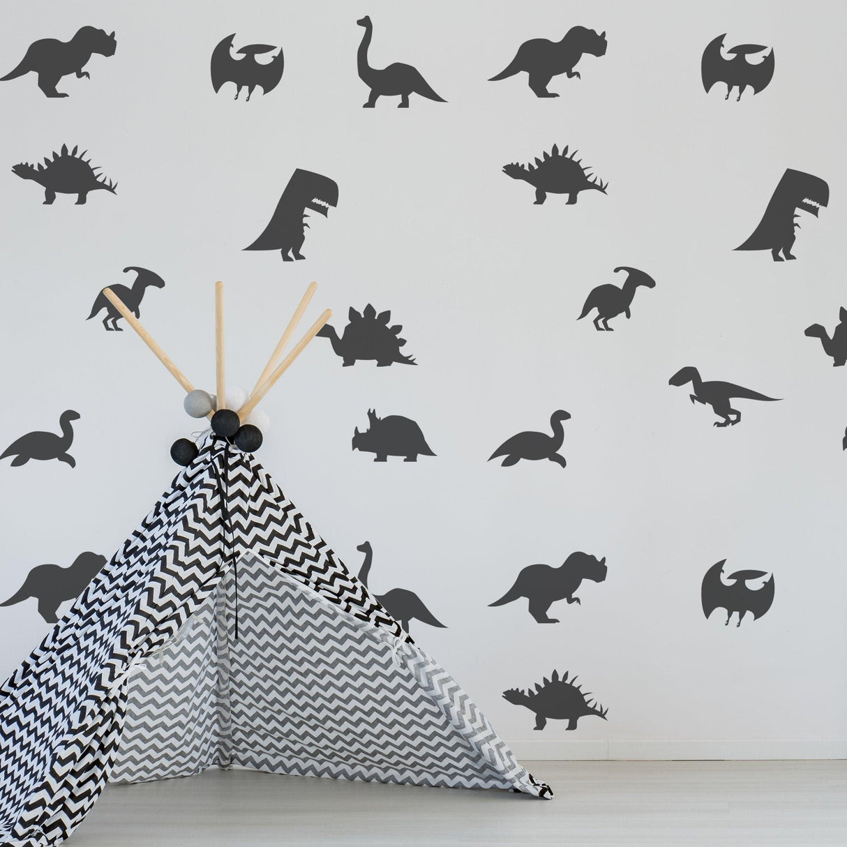 Dinosaur silhouette wall decals in a nursery with a patterned play tent, adding whimsical decor to baby rooms.