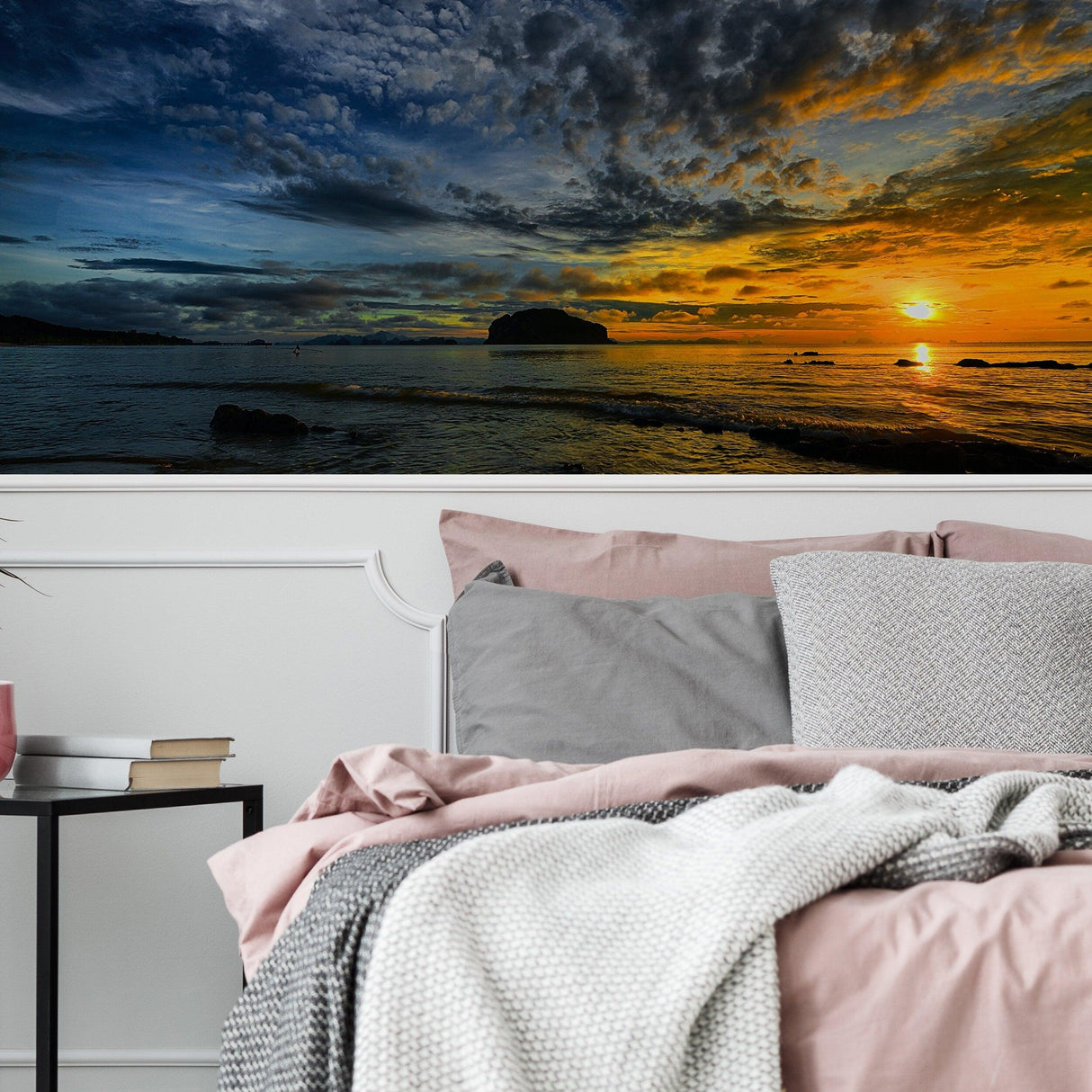 Serene sunset wallpaper decal above a cozy bed with soft pillows and a knitted blanket.