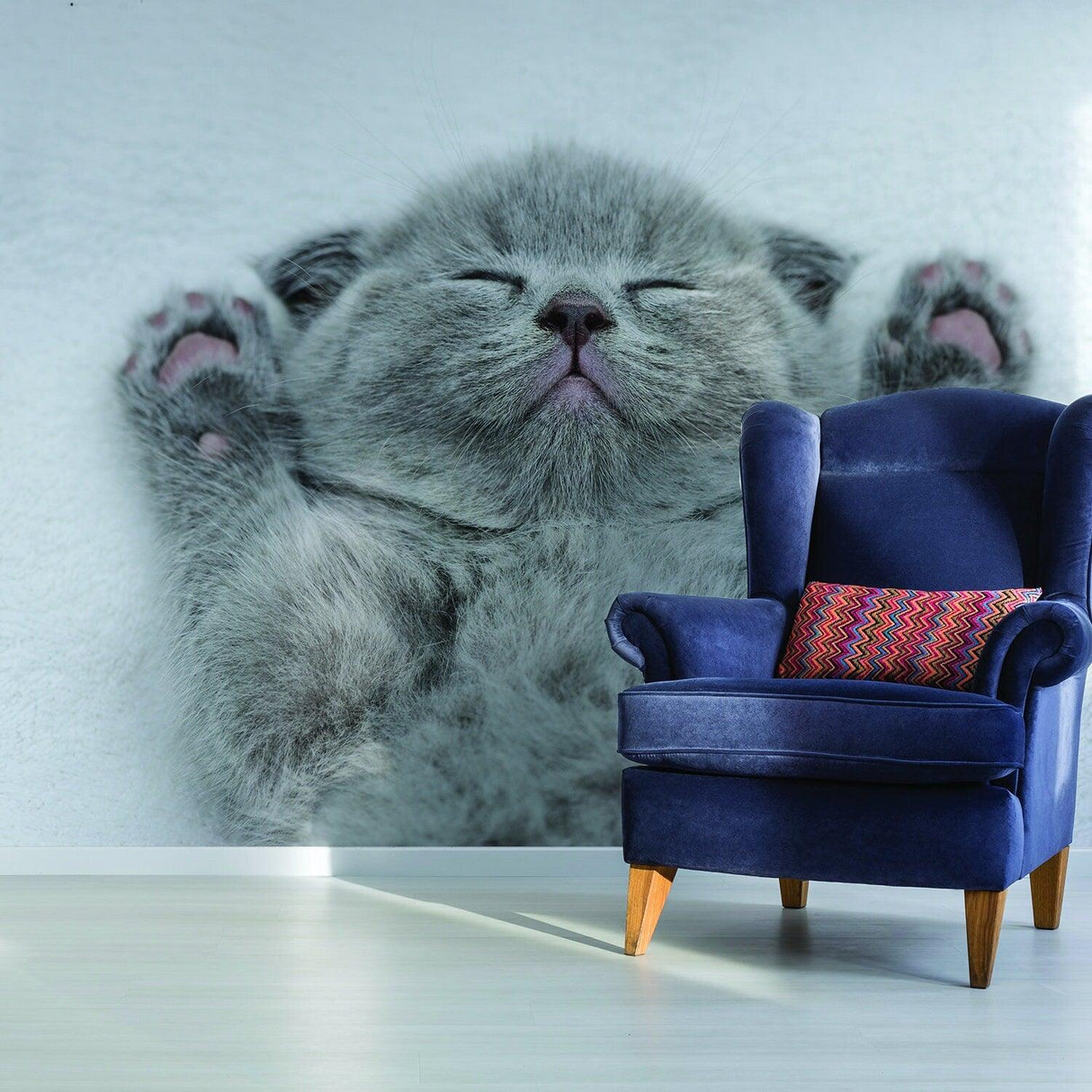 Cozy living room featuring a wall decal of a sleeping gray kitten above a blue armchair.