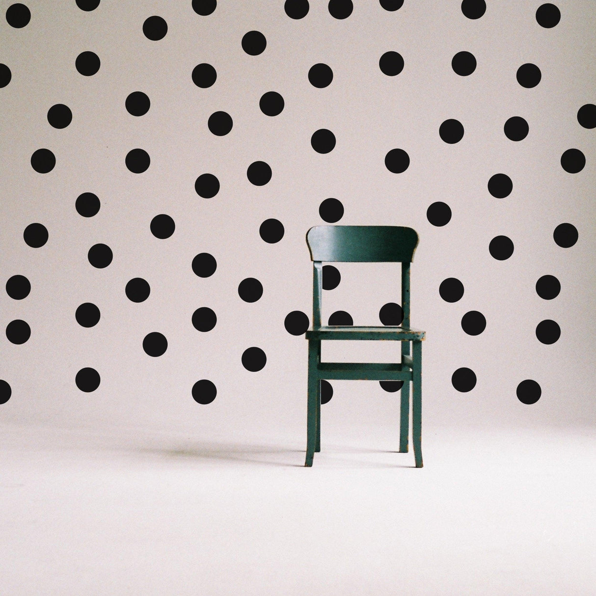 Circle wall stickers - black round dot labels on white wall with a green chair in the foreground.