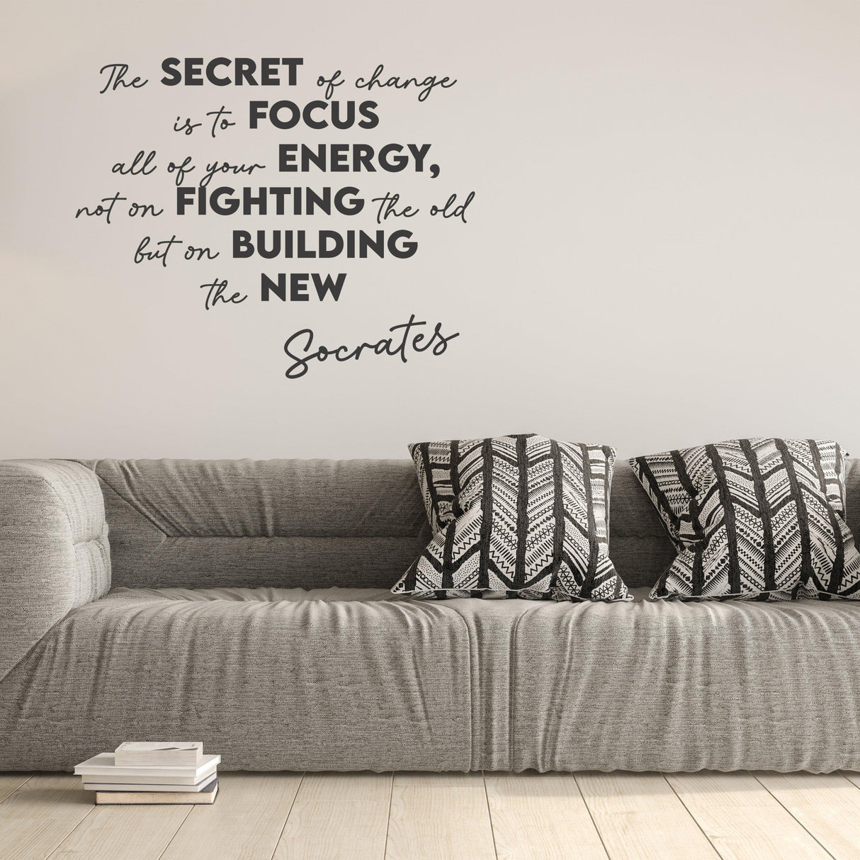 Inspirational wall decal with quote by Socrates on change above a cozy gray sofa with stylish cushions.