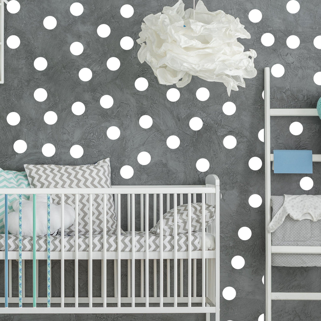 Baby nursery with white round circle dot wall decals, featuring a crib and patterned bedding.