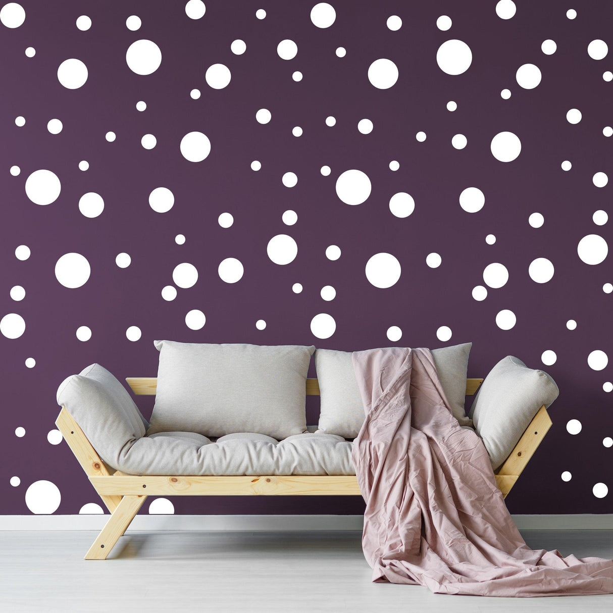 Living room with a couch and purple wall decorated with white round dot decals.