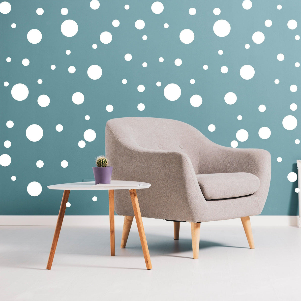 Living room with a comfy chair and a small table, featuring white round stickers on a blue wall.