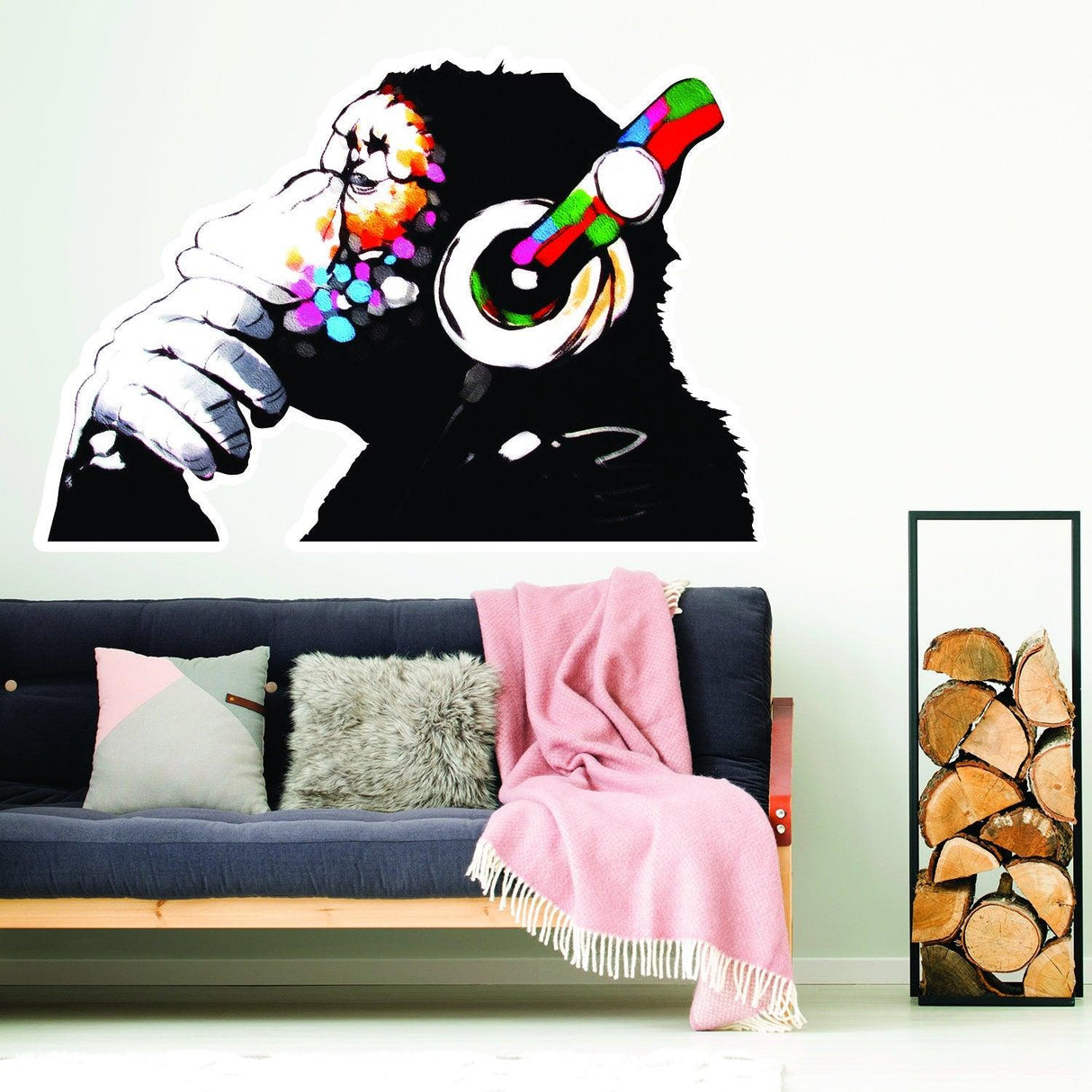 Banksy monkey with headphones wall sticker decor above cozy couch and blanket.