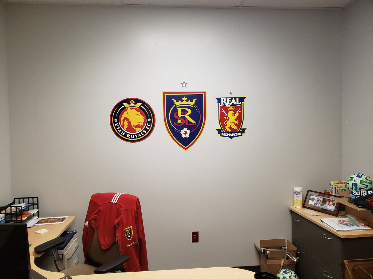 Vinyl wall decals featuring soccer team logos on an office wall behind a desk.