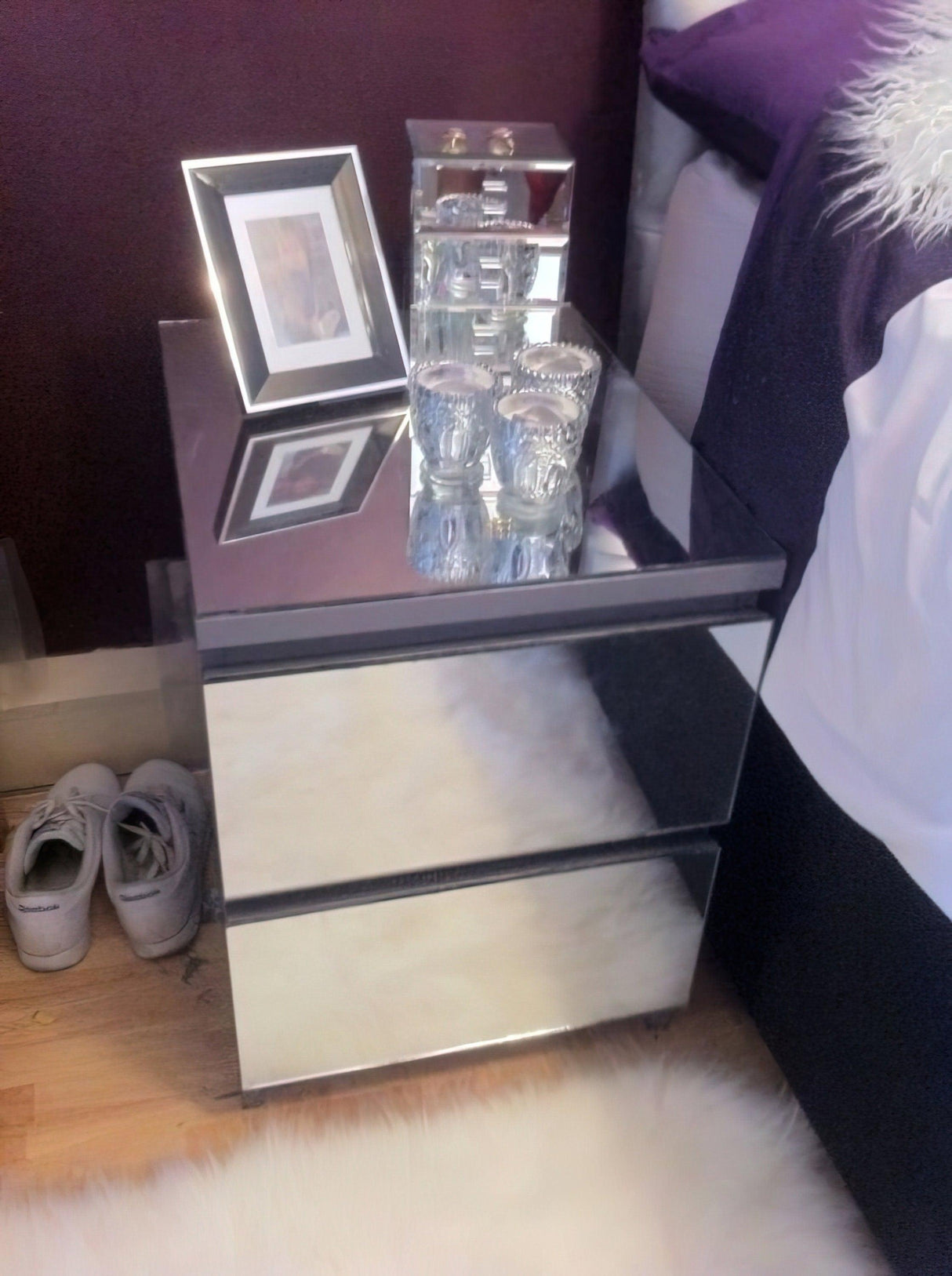 Mirrored metallic nightstand with photo frame and decorative candles, enhancing interior style and glamour.