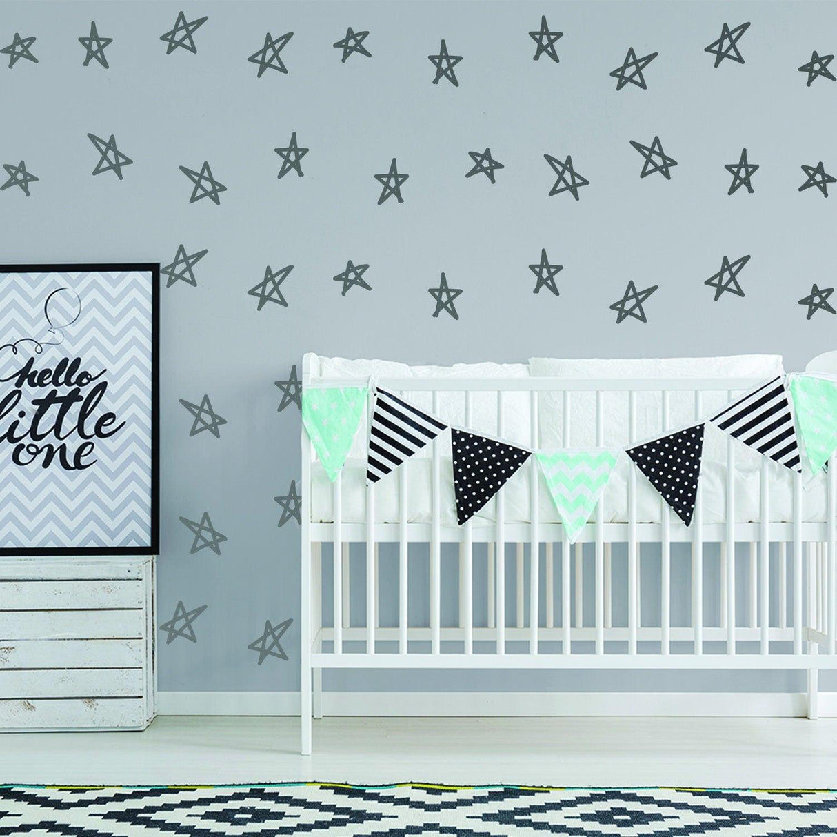 Nursery with removable star wall decals, crib with decorative bunting and framed art, whimsical and charming design.