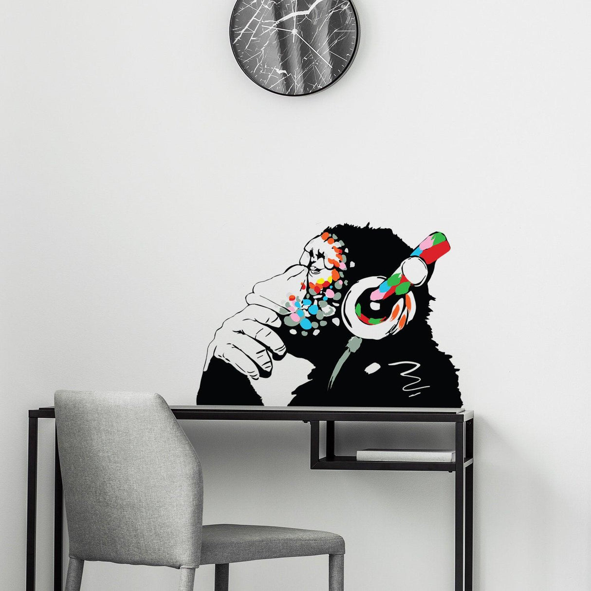 Banksy monkey wall art sticker decal with colorful headphones on a modern office desk.