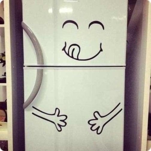 Funny happy face vinyl sticker on a refrigerator door, adding humor to kitchen decor.