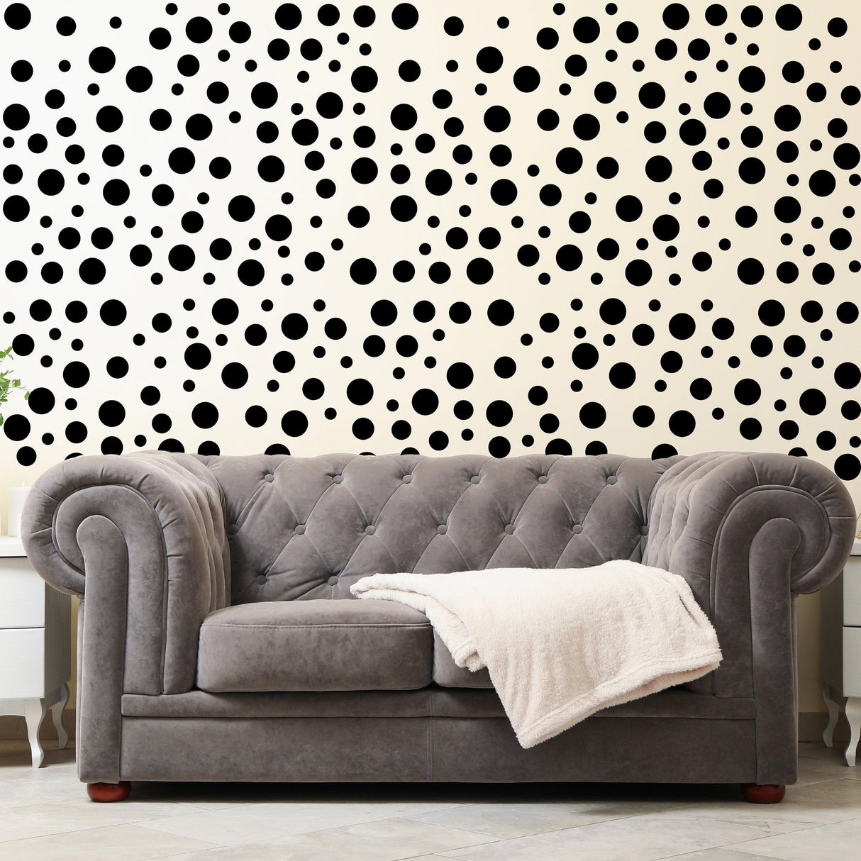 Chic living room featuring black polka dot wall decals behind a plush gray couch with a cozy blanket.
