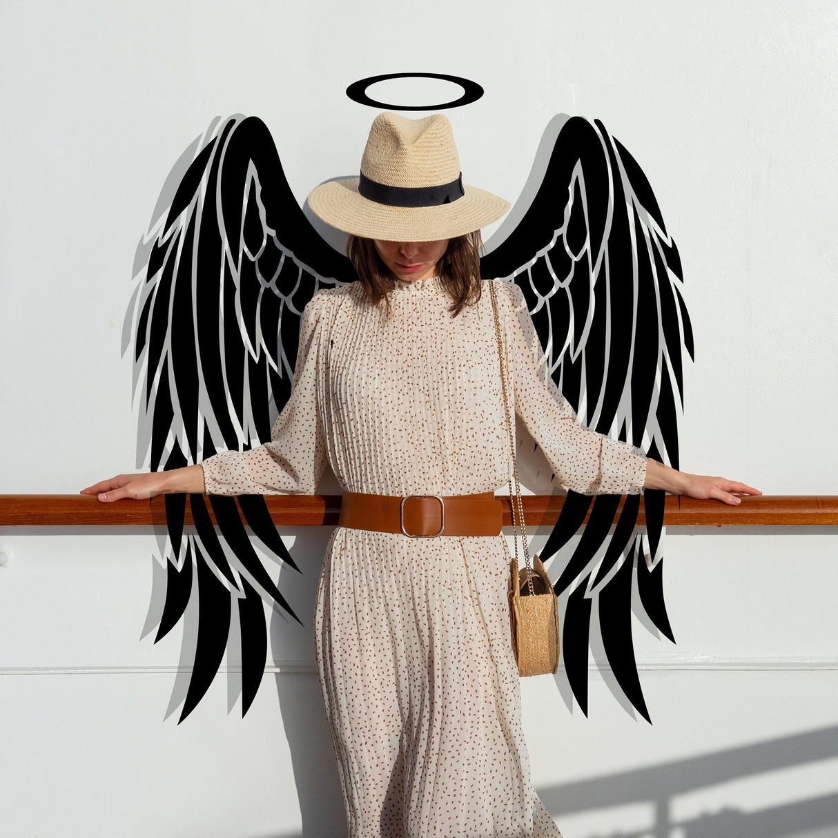 Woman in a hat poses with angel wings vinyl decal, adding a whimsical touch to her outfit and surroundings.
