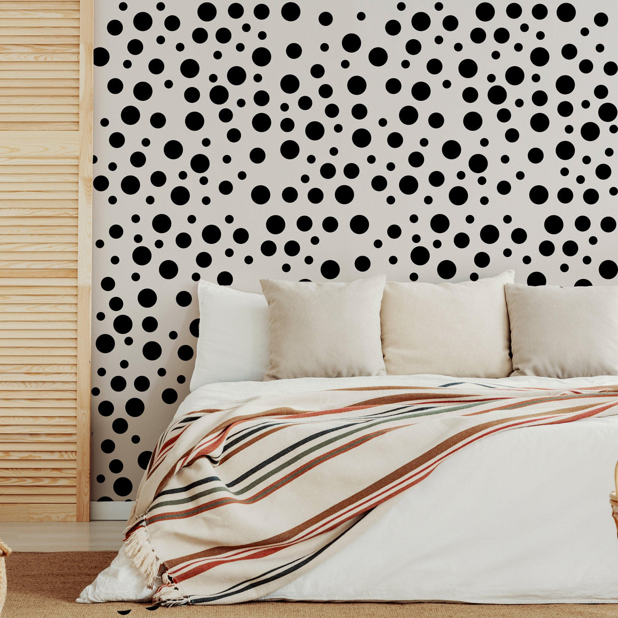 Polka dots wall decals in black on light wall backdrop, adding charm to a cozy bedroom with white bedding.
