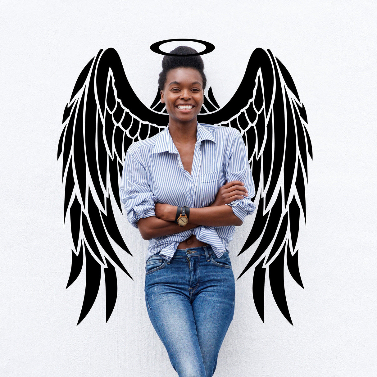 Smiling woman standing in front of black angel wings vinyl decal on white wall, showcasing whimsical wall decor.