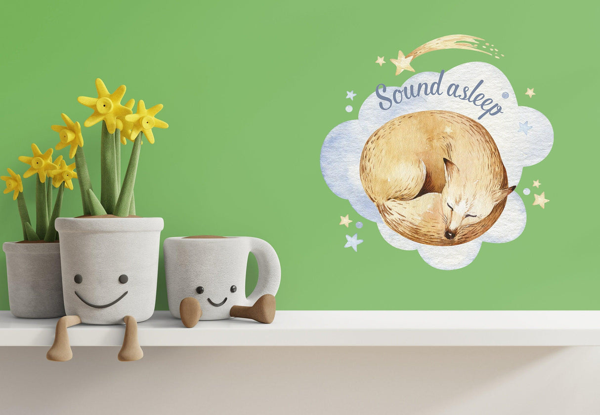 Cute wall decal of a sleeping fox with the text 'Sound asleep', surrounded by stars on a green nursery wall.
