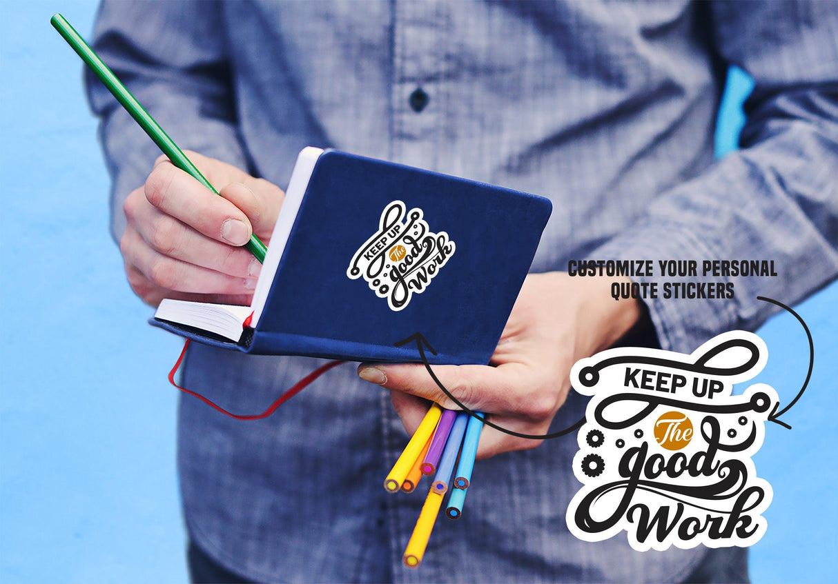 Person holding a notebook with colorful pens, featuring a customized quote sticker saying 'Keep Up the Good Work'.