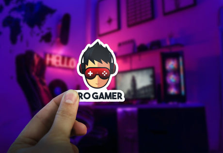 Hand holding a 'Pro Gamer' vinyl sticker in a colorful gaming setup with monitors.