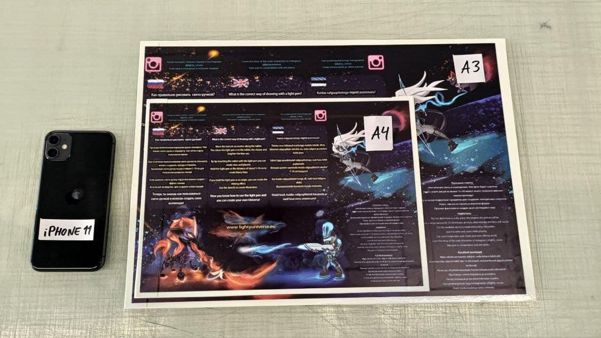 Smartphone next to two colorful printed posters with sci-fi designs labeled A3 and A4.