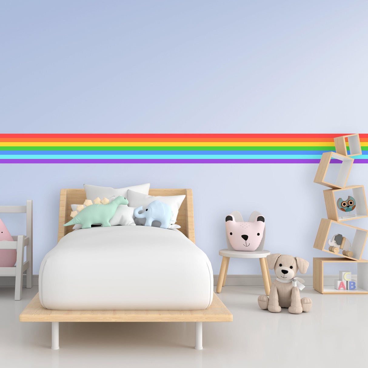 Rainbow Stripe Sticker on nursery wall, colorful vinyl decal above bed with plush toys and decorations.