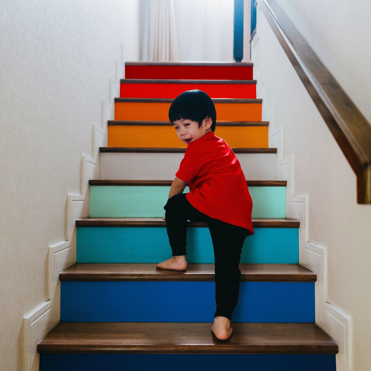 Child playing on colorful self-adhesive staircase with gradient stickers, showcasing vibrant colors and playful atmosphere.