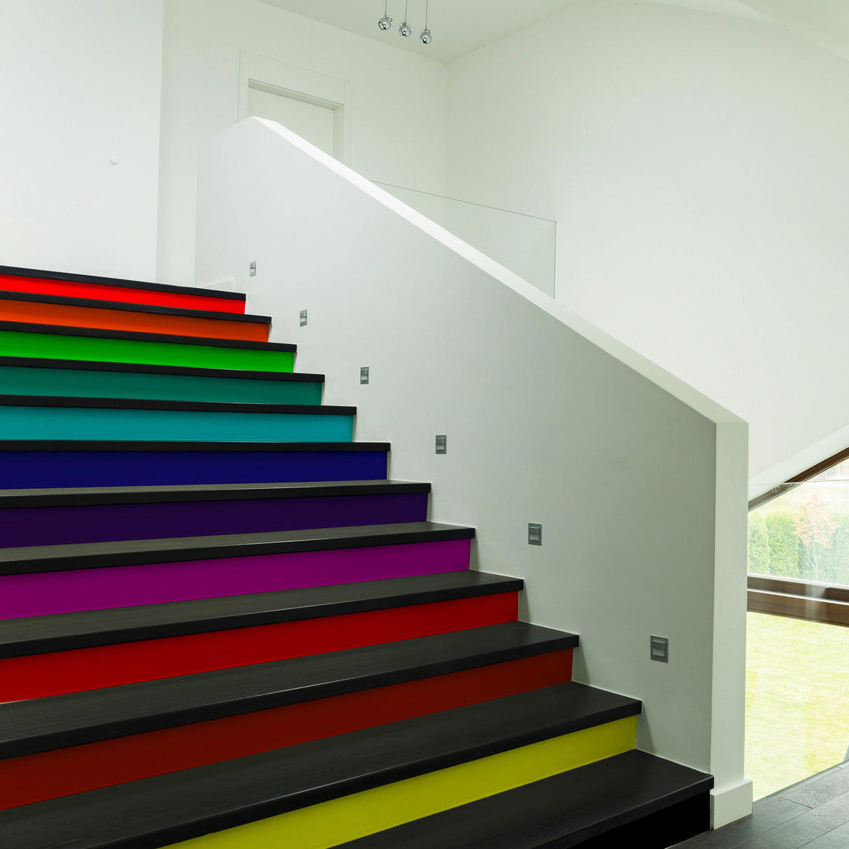 Colorful rainbow self-adhesive stairs risers stickers applied on modern staircase, enhancing home decor.