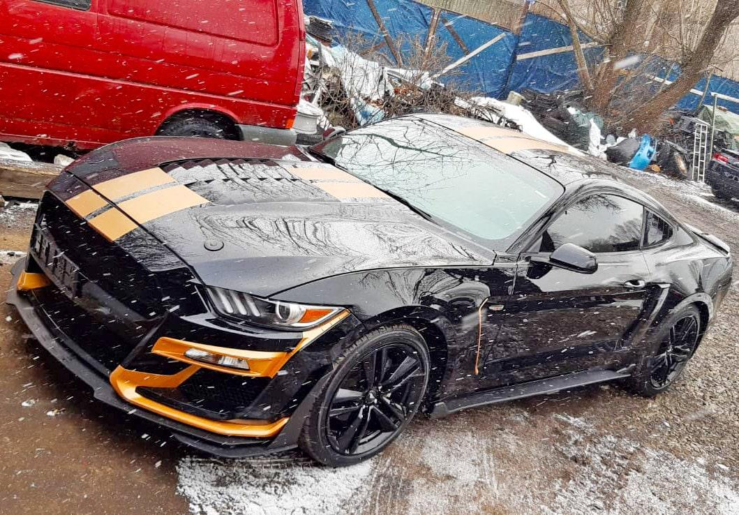 Sleek black sports car with orange racing stripes, showcasing a bold and sporty appearance in a snowy setting.