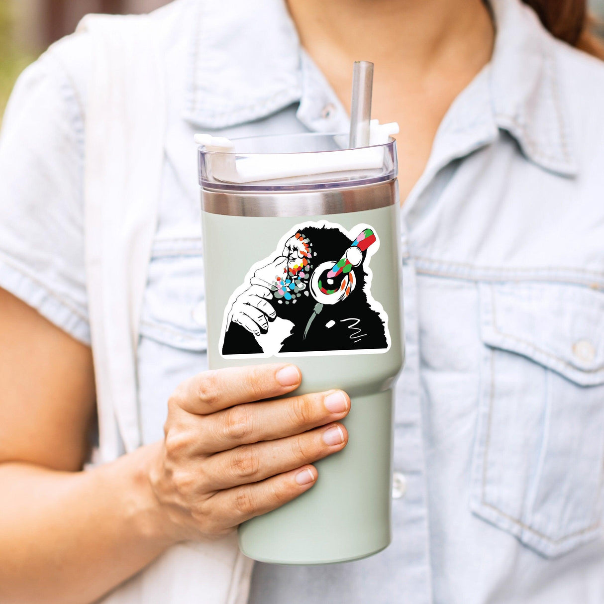 Person holding a mint green tumbler with a colorful monkey design sticker, perfect for music lovers.