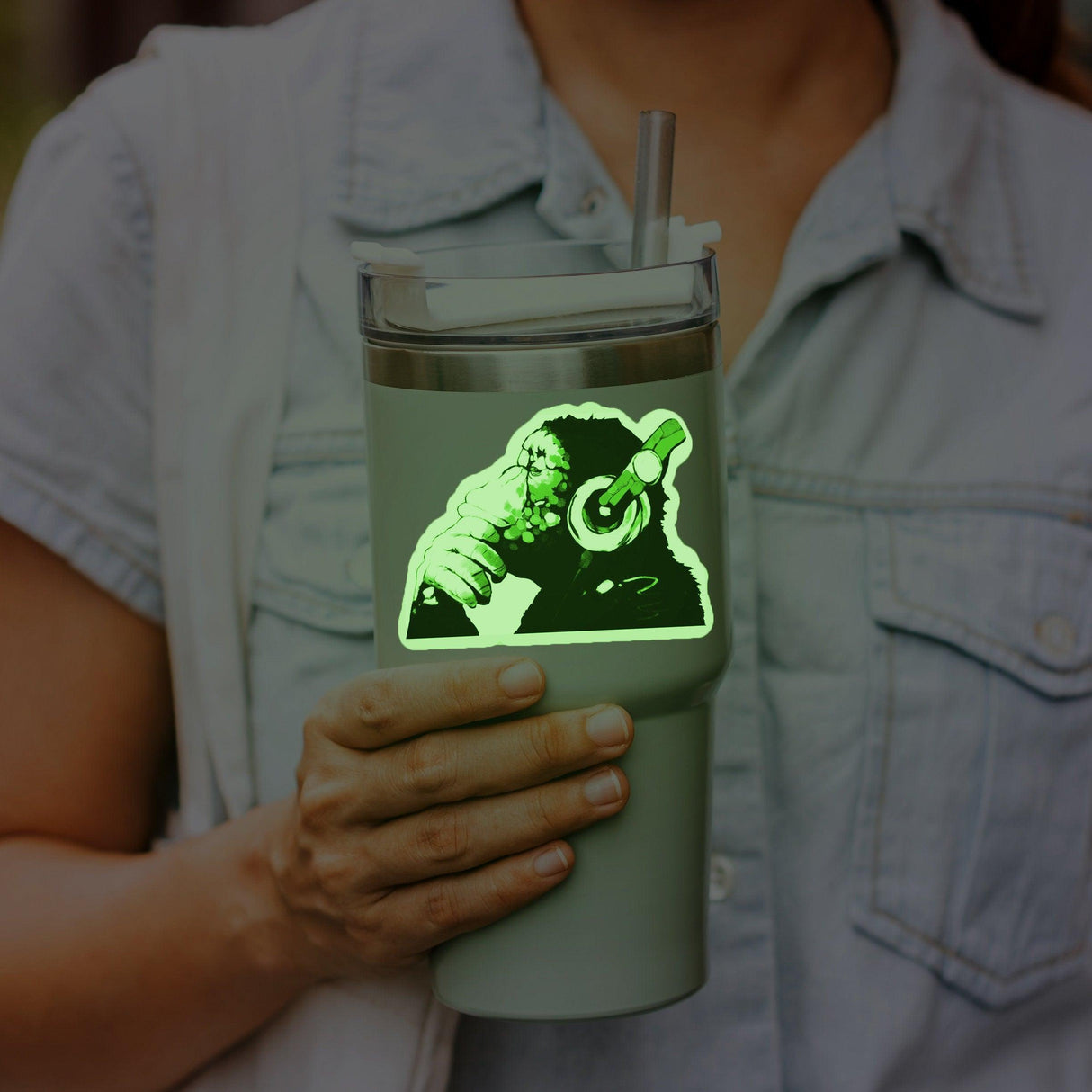 Person holding a glow in the dark tumbler featuring a music monkey with headphones decal.