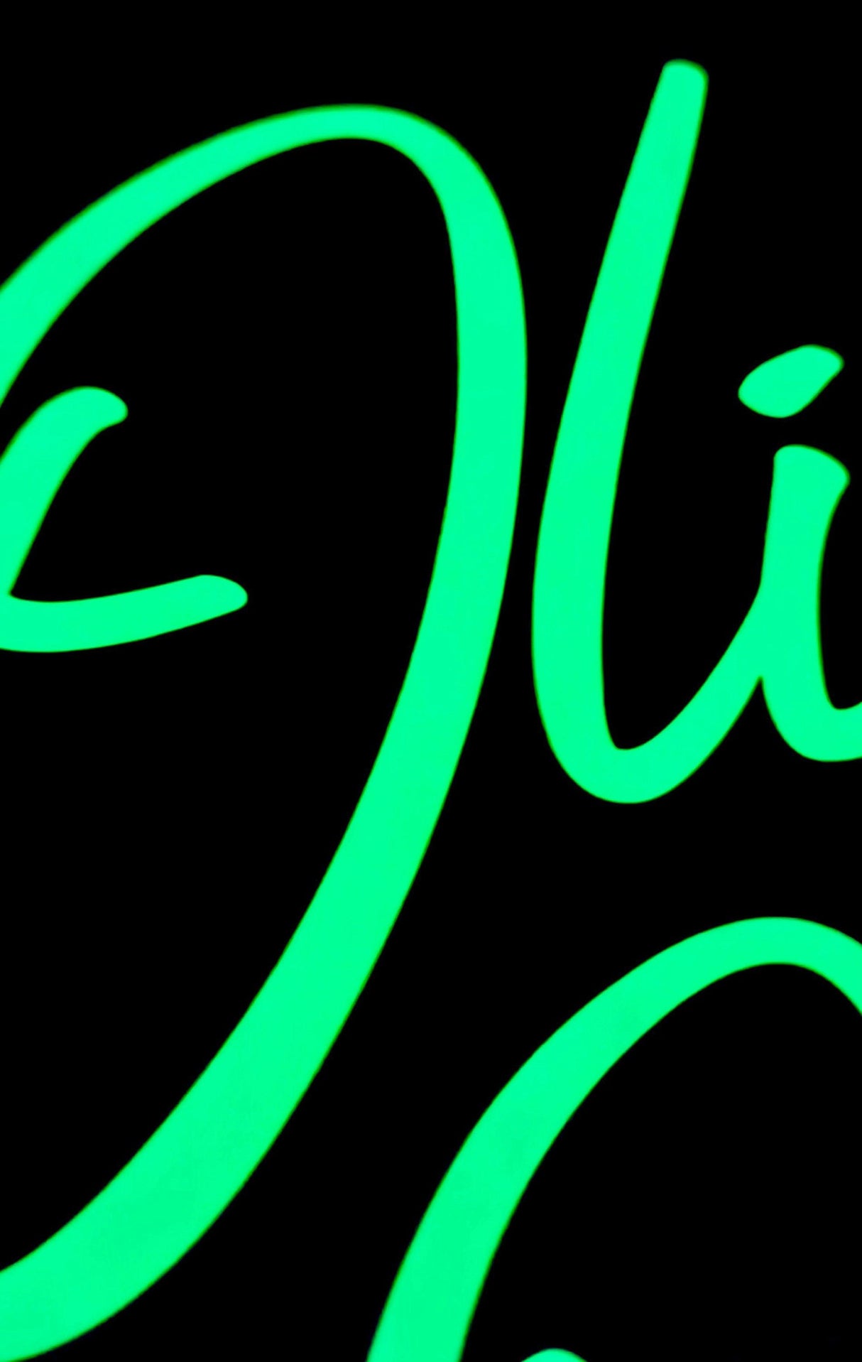 Close-up of glowing green personalized vinyl name decal on dark background.