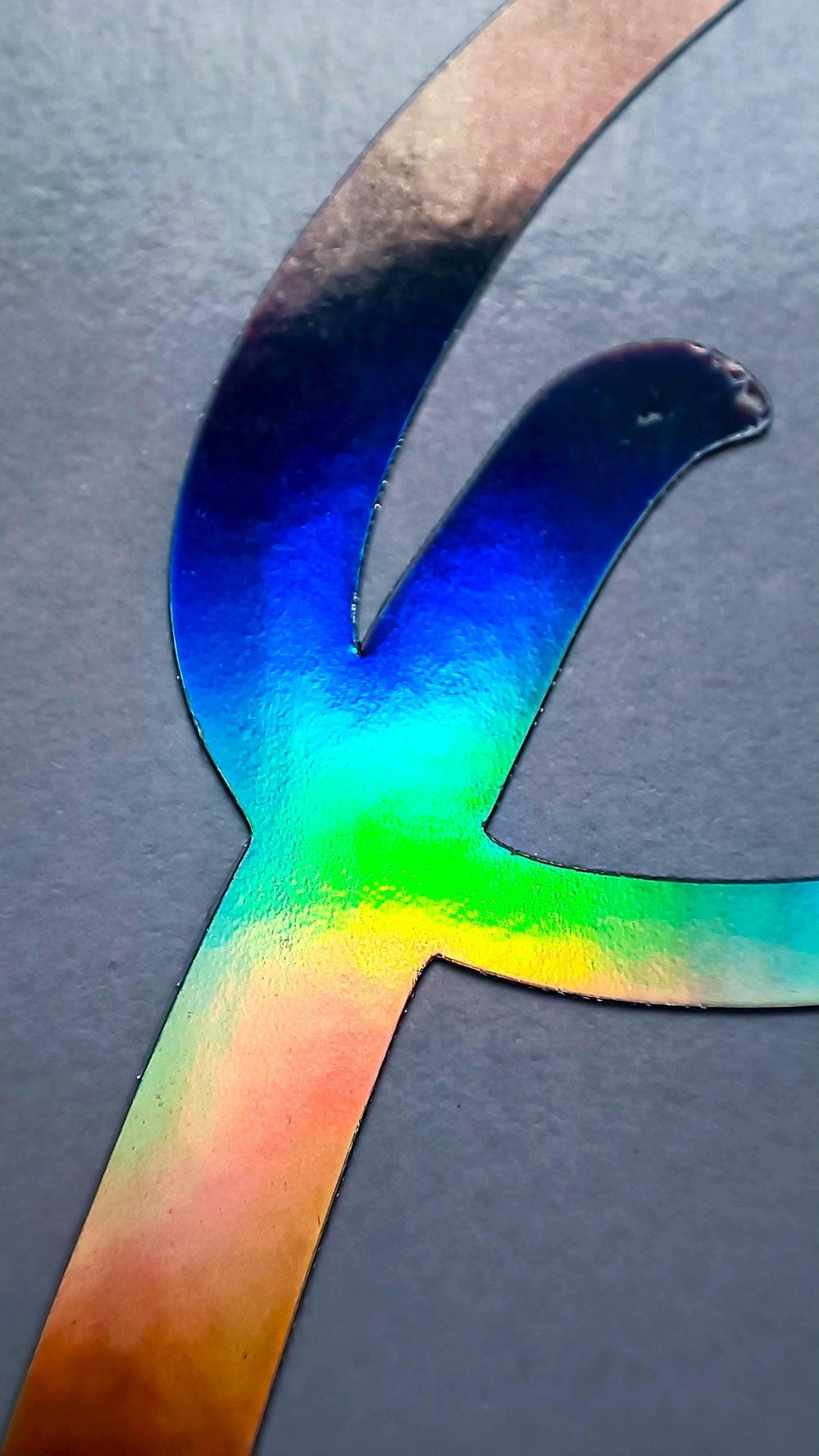 Close-up of a personalized rainbow holographic vinyl name decal showcasing vibrant colors.