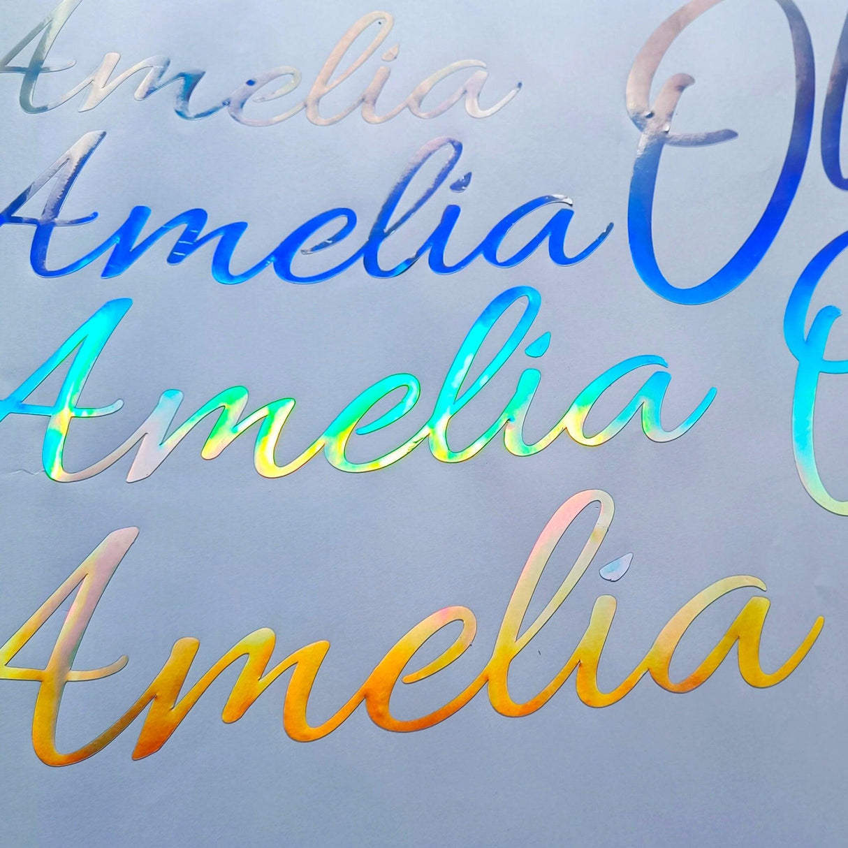 Personalised vinyl name decals showcasing the name 'Amelia' in rainbow holographic finish.